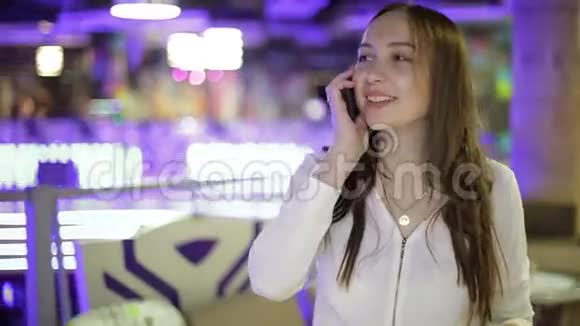 一个漂亮的黑发女孩在购物中心用手机聊天视频的预览图