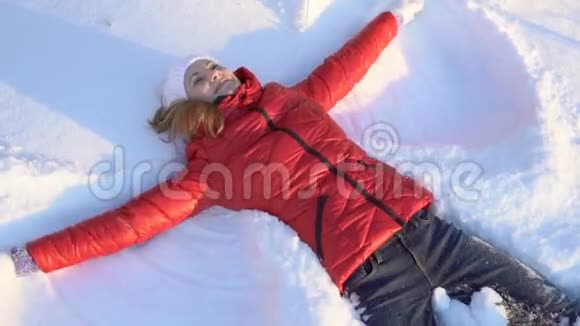 迷人的年轻女子在冬季公园里做雪天使玩得很开心微笑着慢动作视频的预览图