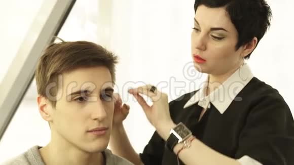 女性发型师在美发沙龙做男性发型关闭理发师在工作期间做男性发型视频的预览图