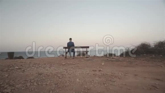坐在面向大海的长凳上的人视频的预览图