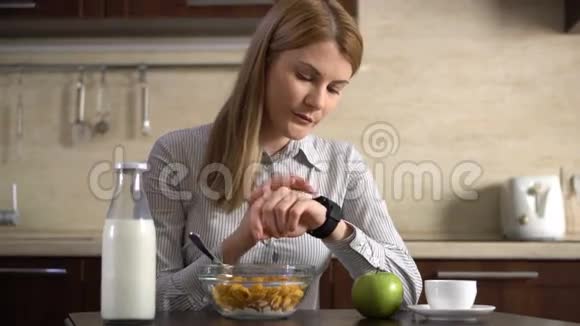 美丽迷人的女商人吃早餐通过她的智能手表发送语音信息视频的预览图