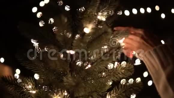 女性在圣诞树上装饰灯背景是bokeh灯视频的预览图