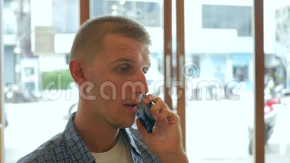 年轻英俊的男人在咖啡厅喝着抹茶在手机上聊天高清慢动作生活方式视频的预览图