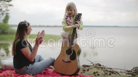 慢动作金发女孩站着弹吉他她的母亲视频的预览图