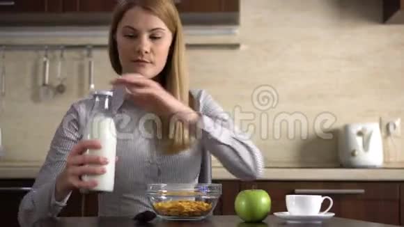 漂亮的年轻漂亮的女商人把牛奶倒进厨房里的一碗玉米片里视频的预览图