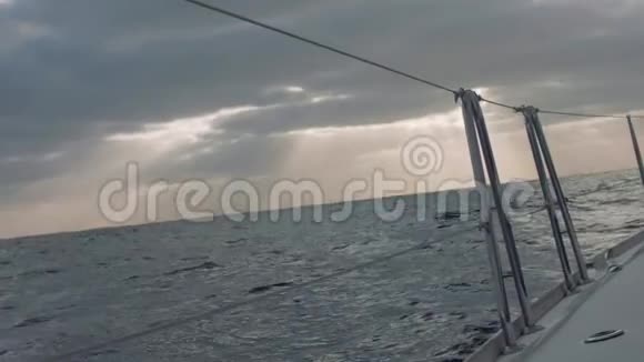从帆船左侧板上看海洋太阳光线穿过云层照亮海面视频的预览图
