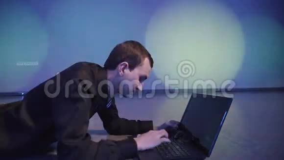 一个年轻人在关掉笔记本电脑的键盘上打字躺在夜总会的地板上视频的预览图