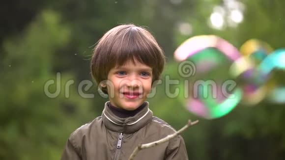 特写一个非常可爱的小男孩的肖像他捕捉肥皂泡慢动作视频的预览图