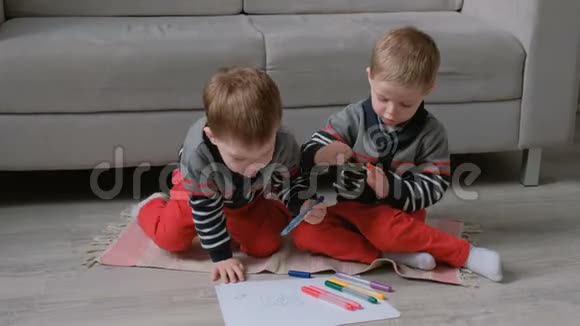 两个双胞胎兄弟蹒跚学步的孩子一起画坐在地板上的标记视频的预览图