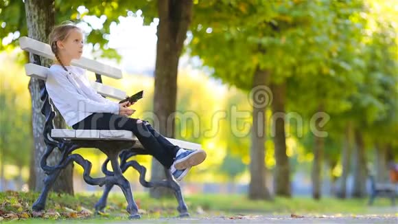 可爱的孩子坐在美丽的秋日户外失去了思考小女孩倒在长凳上视频的预览图