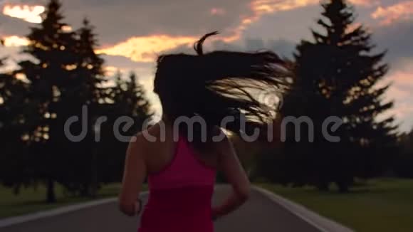女人在日出的天空背景下奔跑慢动作的跑步女性剪影视频的预览图