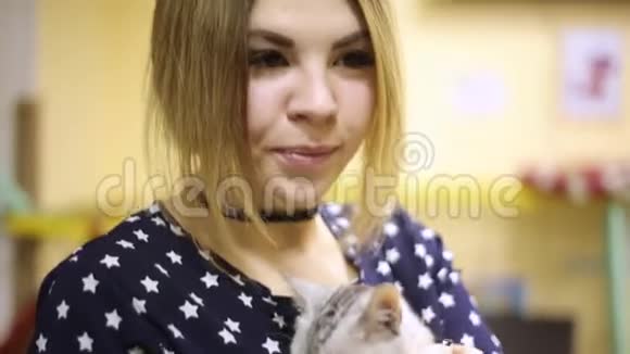 亚洲女孩抚摸着一只担心的灰色猫看着相机微笑着视频的预览图
