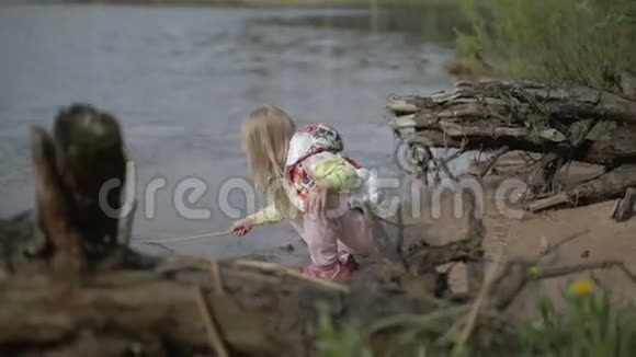 漂亮的金发女孩脸上有图案在湖里钓鱼视频的预览图