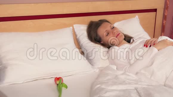 女人在床上醒来发现郁金香花快乐的女性微笑视频的预览图