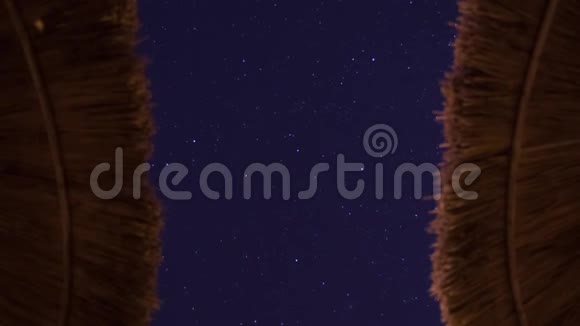星迹追踪深蓝的天空背景景色的痕迹前景上对称的海滩伞彗星视频的预览图