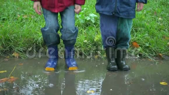 两个男孩在泥泞的水坑里跳在一起动作缓慢视频的预览图