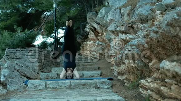 女人站在他的头上的石阶上的运动垫视频的预览图