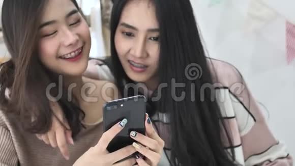 美丽的亚洲女孩用移动手机微笑的慢动作视频的预览图