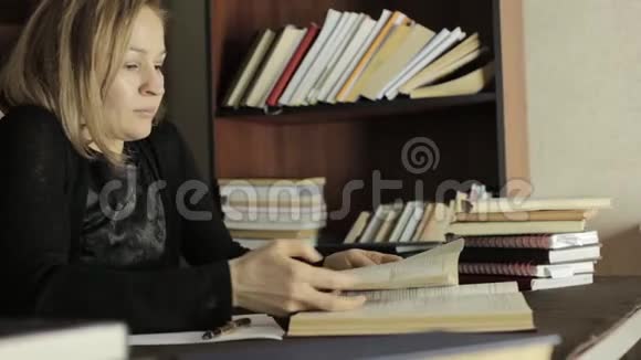 疲惫的学生在大学里在图书馆学习坐在书桌前抓着她的头的女学生视频的预览图