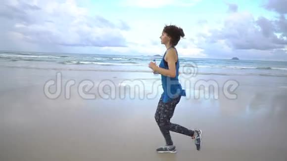 健康活跃的年轻女子在日出时沿着海岸线奔跑女性慢跑视频的预览图