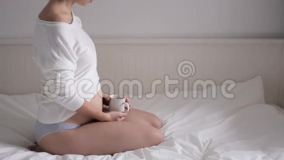 穿着白色t恤坐在白色床上的孕妇视频的预览图