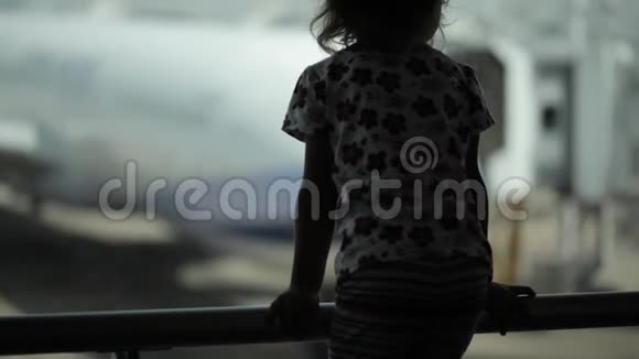 儿童在机场靠窗看飞机等待飞行时间视频的预览图