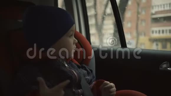 男孩坐在孩子的座位上在雨天看着窗外视频的预览图