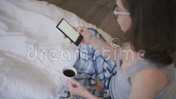 年轻女性喝咖啡使用智能手机视频的预览图