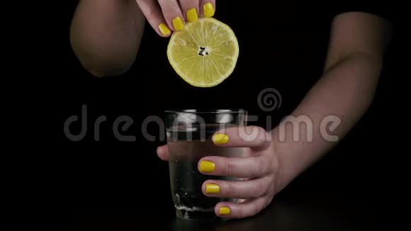 女人手把柠檬扔进玻璃杯里慢动作视频的预览图