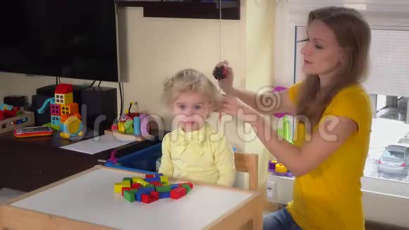 母亲在家里擦着女儿坐在小桌旁视频的预览图