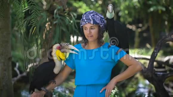 巴厘岛鸟类和爬行动物公园里的女孩她心情很好与鸟儿合影视频的预览图