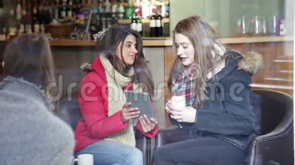 两个女人在咖啡馆里用数码平板电脑视频的预览图