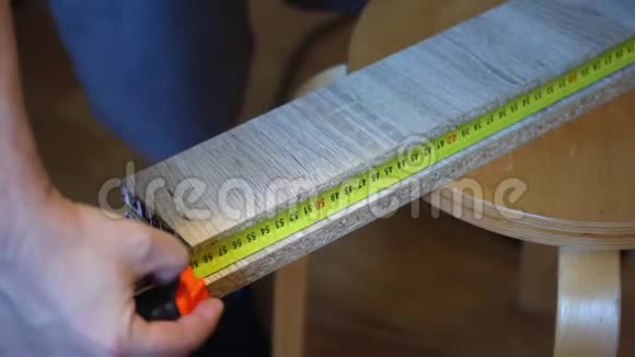 这个人用卷尺测量木板上的距离并标记标记家庭工作与家具视频的预览图