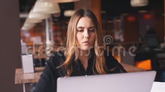 严肃的女商人穿着黑色衬衫在笔记本电脑上工作在笔记本上记笔记视频的预览图