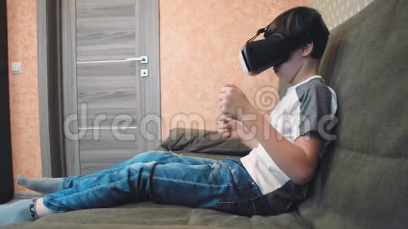 坐在沙发上的小男孩用虚拟现实耳机进行调色游戏视频的预览图