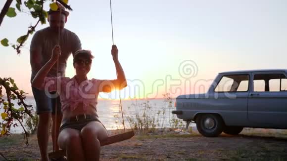 年轻夫妇到海滨河的浪漫之旅日落时海上跷跷板的女孩夏天的情人休息视频的预览图