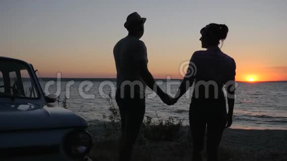 夕阳西下的海滨浪漫情侣之旅海上年轻情侣的夏日休憩一对一对的剪影视频的预览图