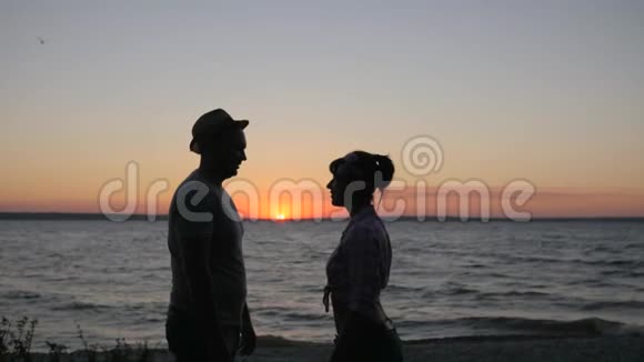在日落时分恋人们亲吻海岸河流在夕阳的映衬下幸福的一对吻吻河堤视频的预览图