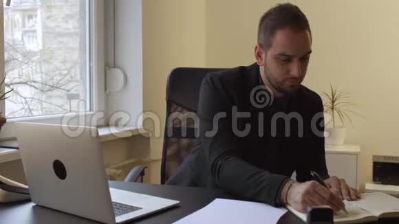在办公室工作的商人在笔记本电脑上做笔记视频的预览图