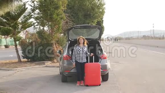 一位年轻的女旅行者她的车旁边放着一个手提箱视频的预览图