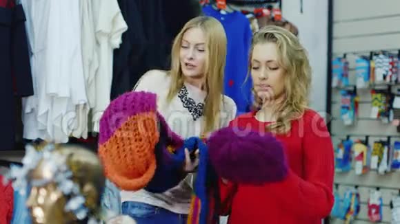 两个女朋友在一家服装店暖和的衣服看看围巾和帽子冬季购物视频的预览图