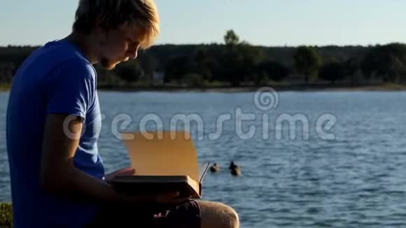 年轻人看照片鸭子在湖边游泳视频的预览图