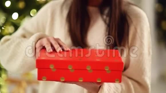 女性手在家打开红盒子无法辨认的布鲁内特打开圣诞礼物背景上模糊的圣诞灯视频的预览图