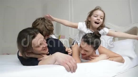 有两个成年人的小男孩和女孩正一起在白人父母的床上放松青年夫妇开支画像视频的预览图