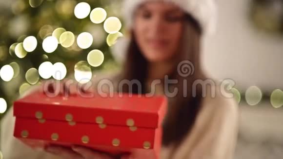 圣诞帽里的漂亮女人对红盒子里的惊喜感到震惊可爱的微笑女孩开启圣诞礼物视频的预览图
