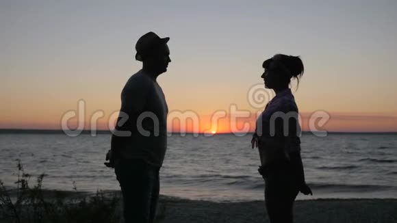 快乐的一对在日落的背景下亲吻河岸在日落的时候亲吻情人的海岸视频的预览图