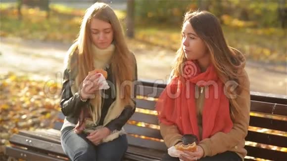 在阳光明媚的秋日午餐休息期间学生们坐在公园的长凳上吃快餐两个惊人视频的预览图