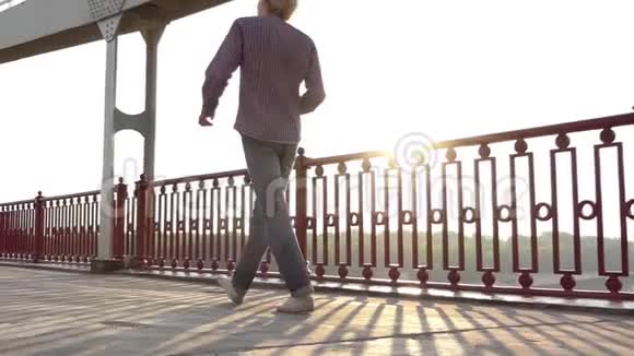 在斯隆莫的夕阳下年轻人带着一辆移动车沿着桥走视频的预览图