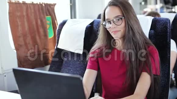 坐在火车上用笔记本电脑的年轻女子视频的预览图