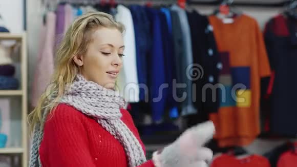 穿红色毛衣的漂亮女人试着用暖和手套它应该在服装店视频的预览图